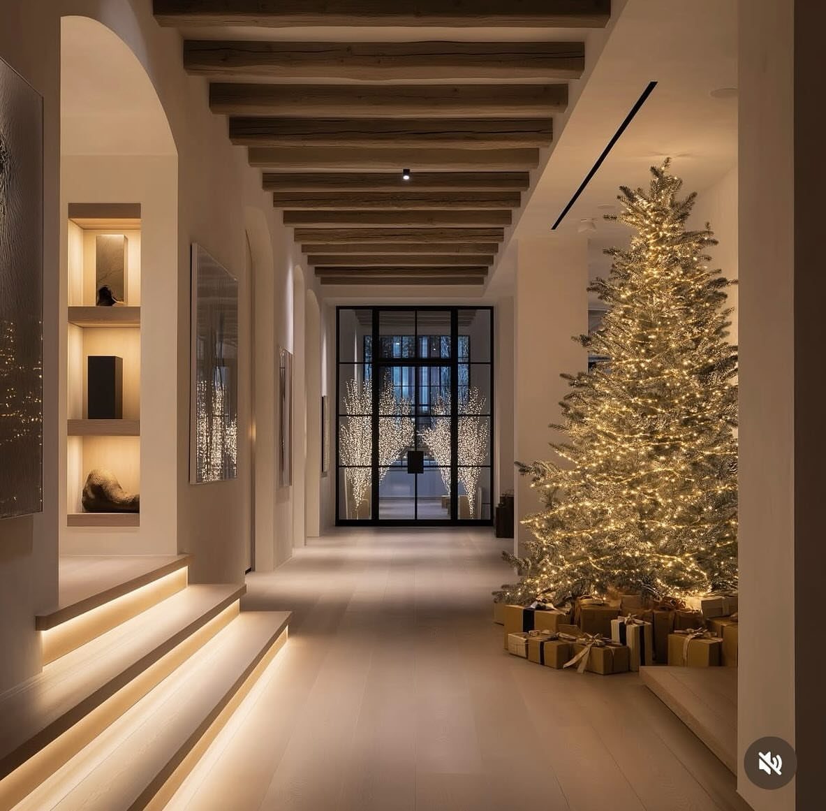 Large Christmas tree with warm white lights in a modern white hallway with beams