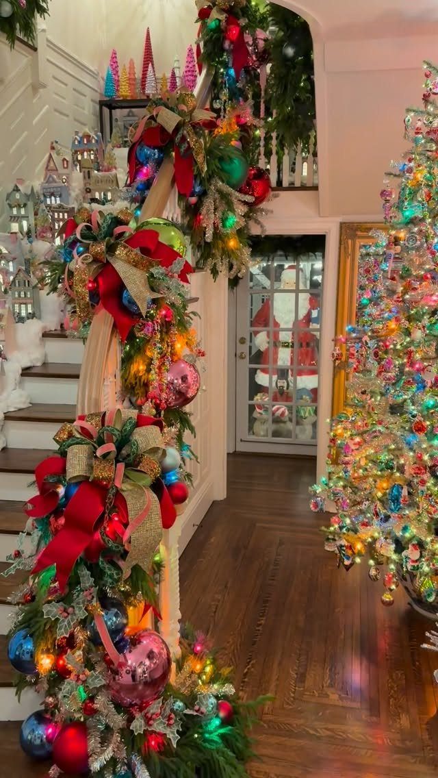 Festive staircase garland with colorful ornaments and a brightly lit Christmas tree nearby.