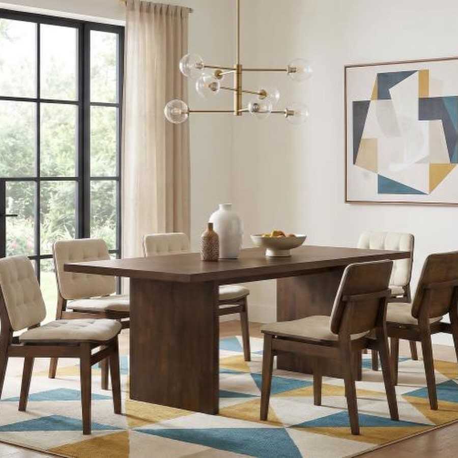 Rectangular wood dining table with six upholstered chairs on a geometric rug.