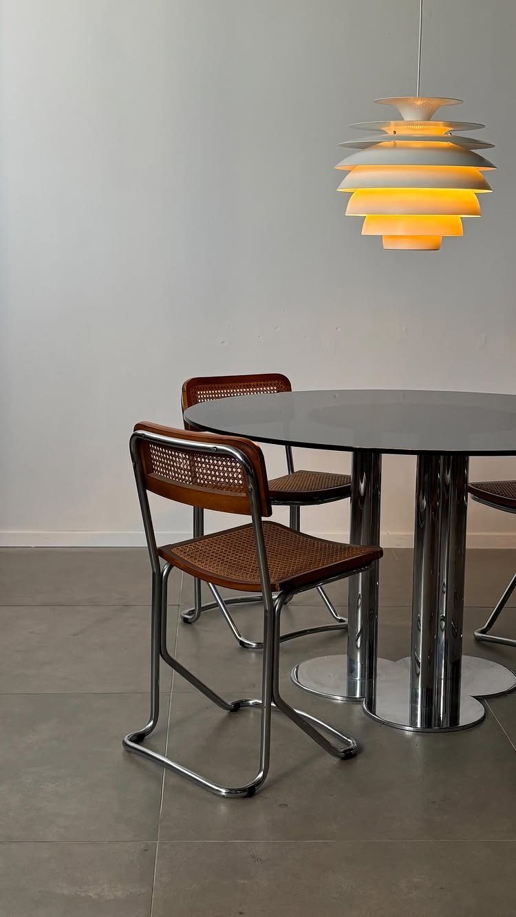 Round dining table with chrome legs and matching cane-seated chrome chairs.