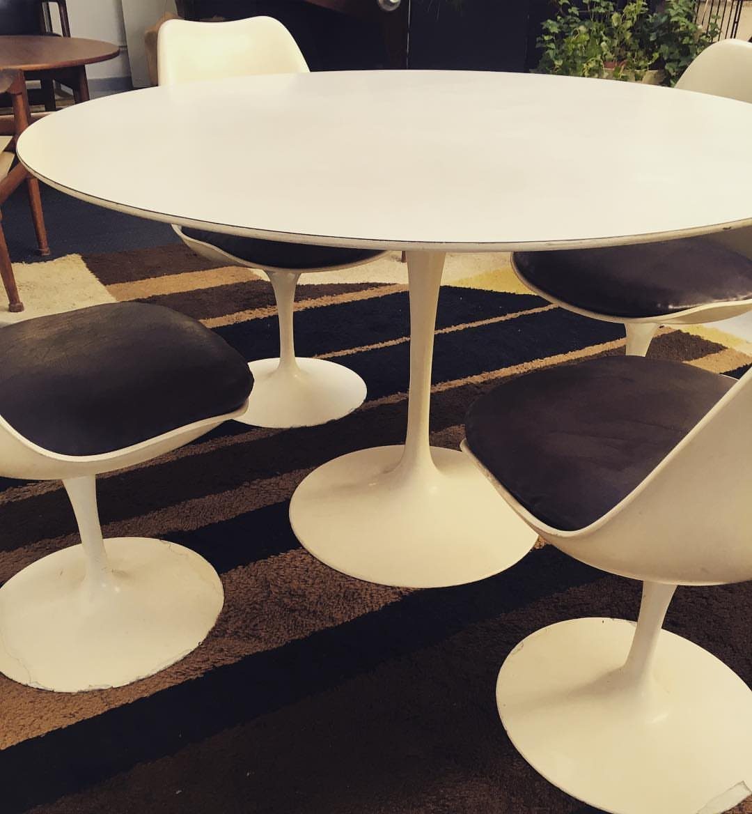 White round tulip dining table and matching chairs on a striped rug.
