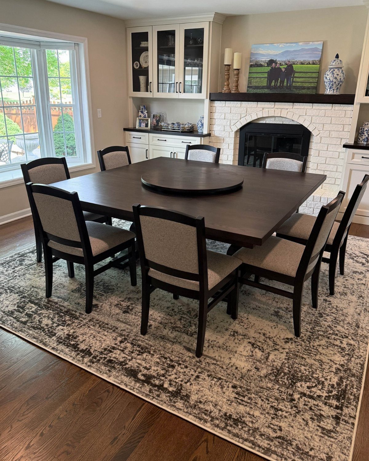 Dark brown rectangular dining table with eight upholstered chairs and a lazy Susan.