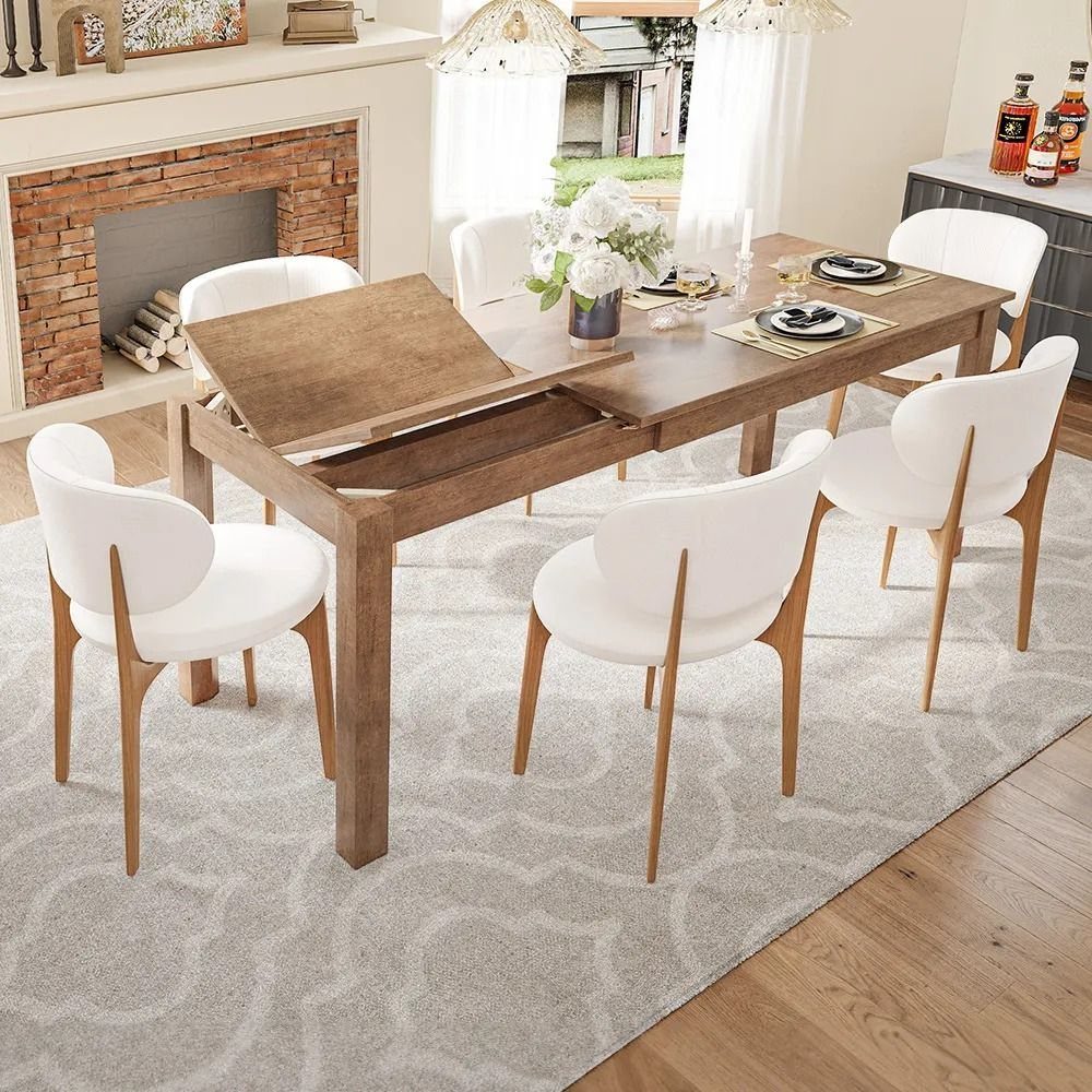 Wooden extendable dining table with white chairs in a bright living room setting.
