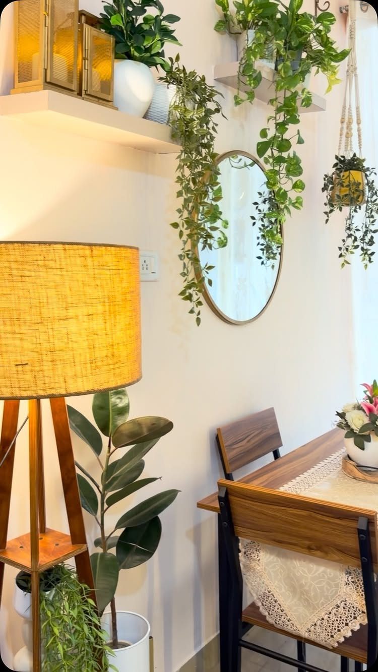 Dining area with wooden furniture, woven lamp, round mirror, and lush green plants.