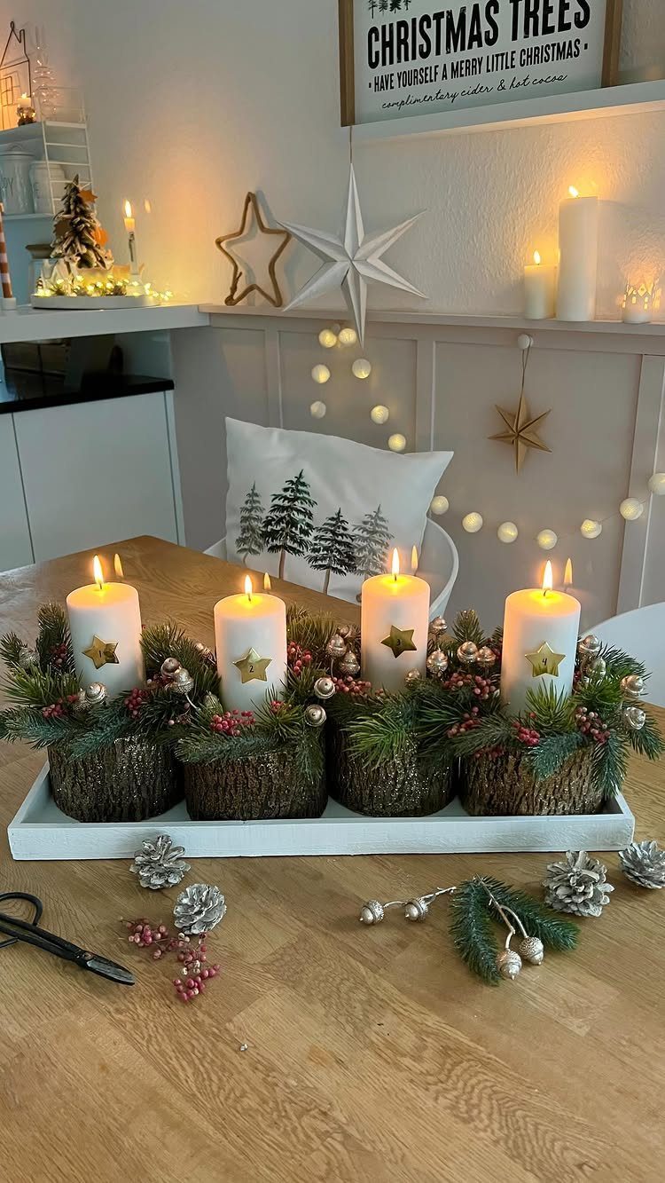 Four white pillar candles in woven baskets with greenery on a white tray.