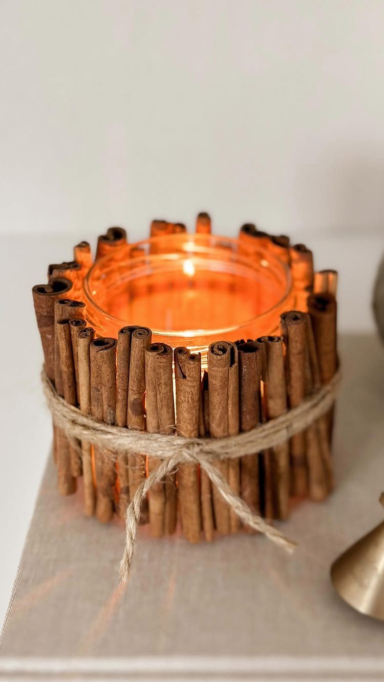 Lit tea light candle surrounded by cinnamon sticks tied with a twine bow.