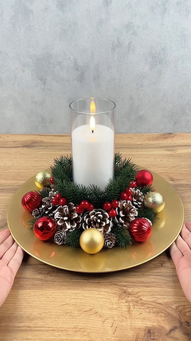 White pillar candle inside a festive evergreen wreath with ornaments and pinecones.