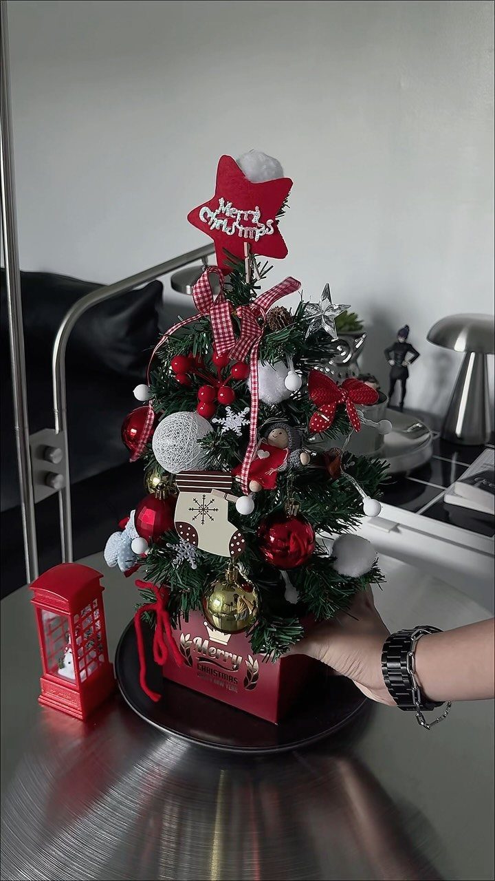 Small decorated Christmas tree with red ornaments on a metallic coffee table