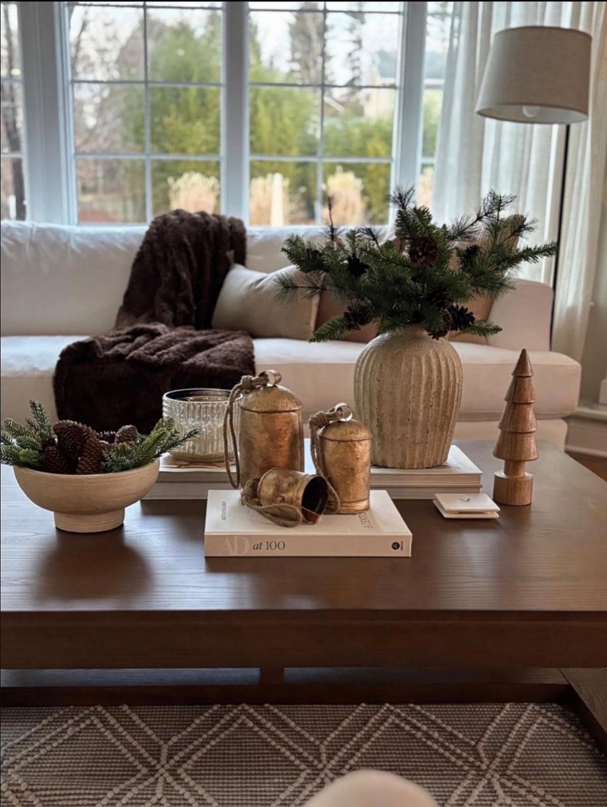 Wooden coffee table with evergreen branches, gold canisters, and a small wooden tree.