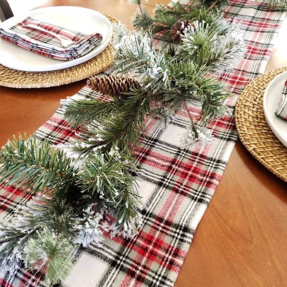 Frosted evergreen garland with pinecones on a red plaid table runner