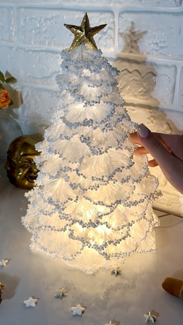 Glowing white decorative Christmas tree with a gold star topper and scattered stars.