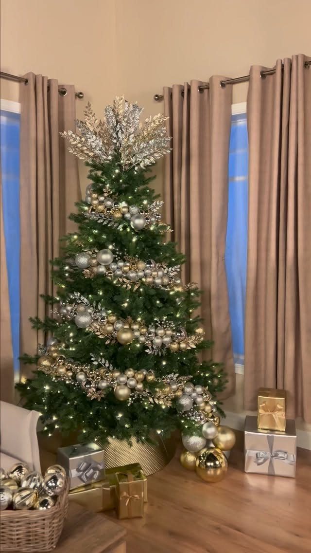 Green Christmas tree decorated with silver and gold ornaments and metallic garlands.