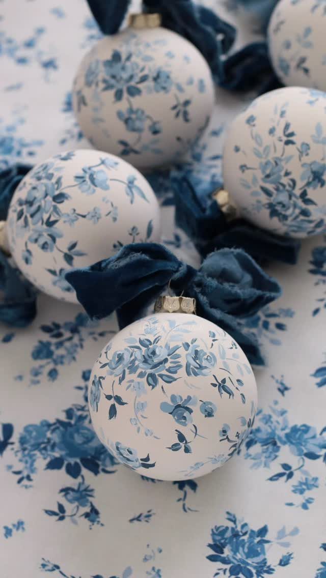 White Christmas ornaments with blue floral patterns and dark blue velvet bows.