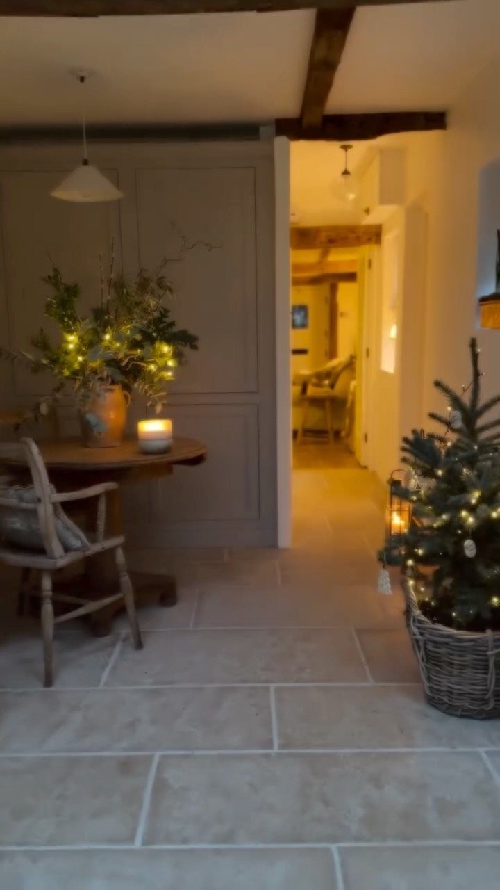 Small green Christmas tree with warm lights in a wicker basket on stone floor
