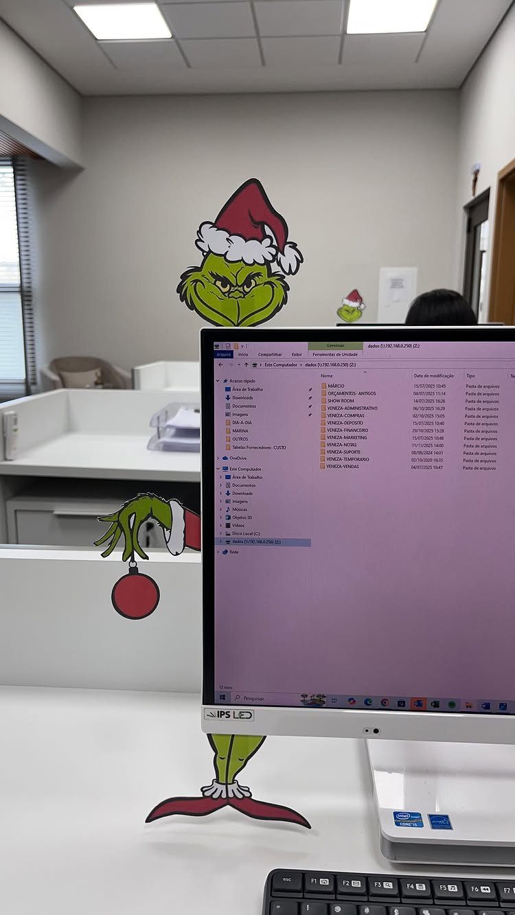 Grinch paper cutouts decorating a computer monitor on a white office desk