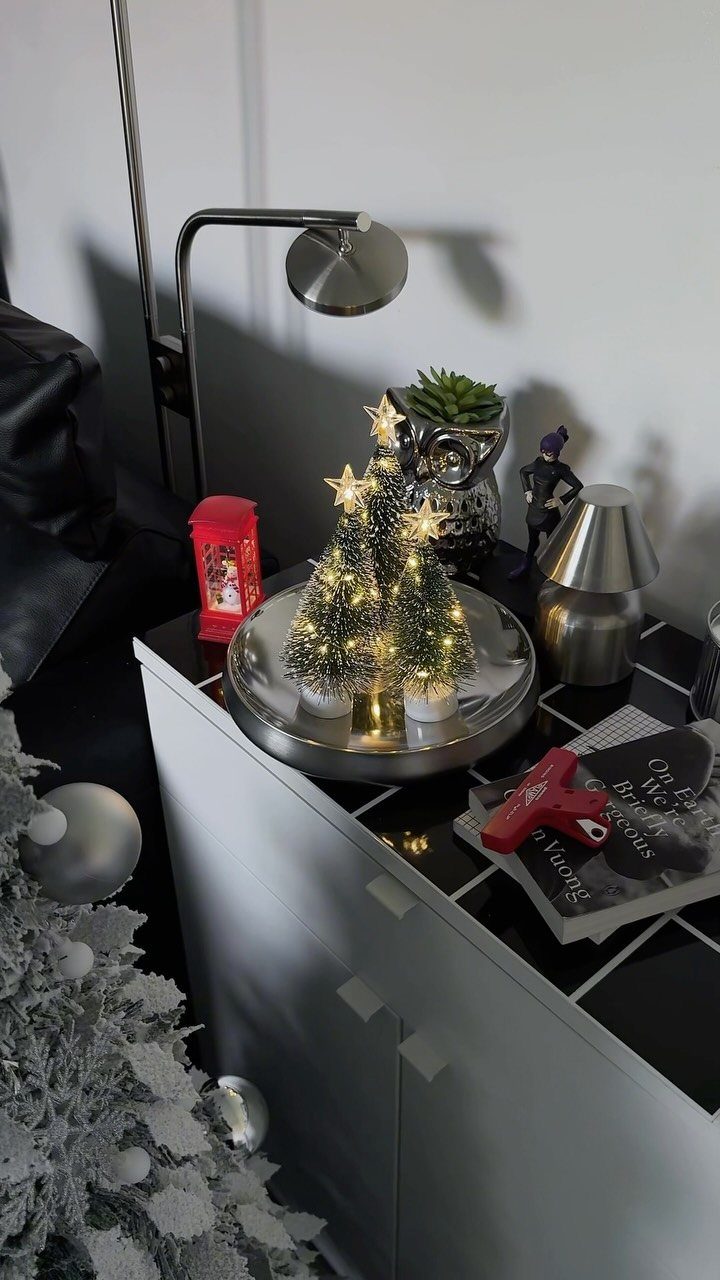 Three small lit Christmas trees with gold stars on a silver tray.