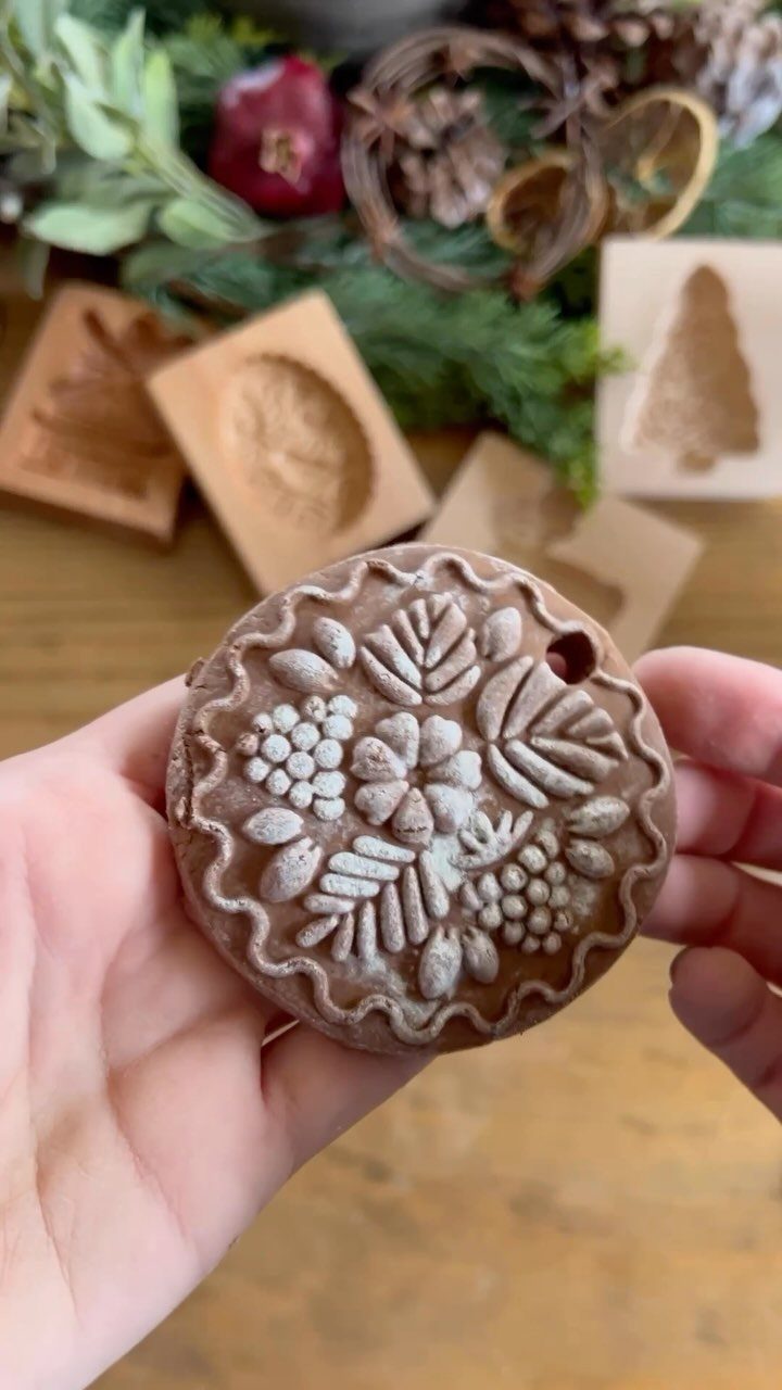 Brown salt dough ornament with embossed floral patterns held in two hands.