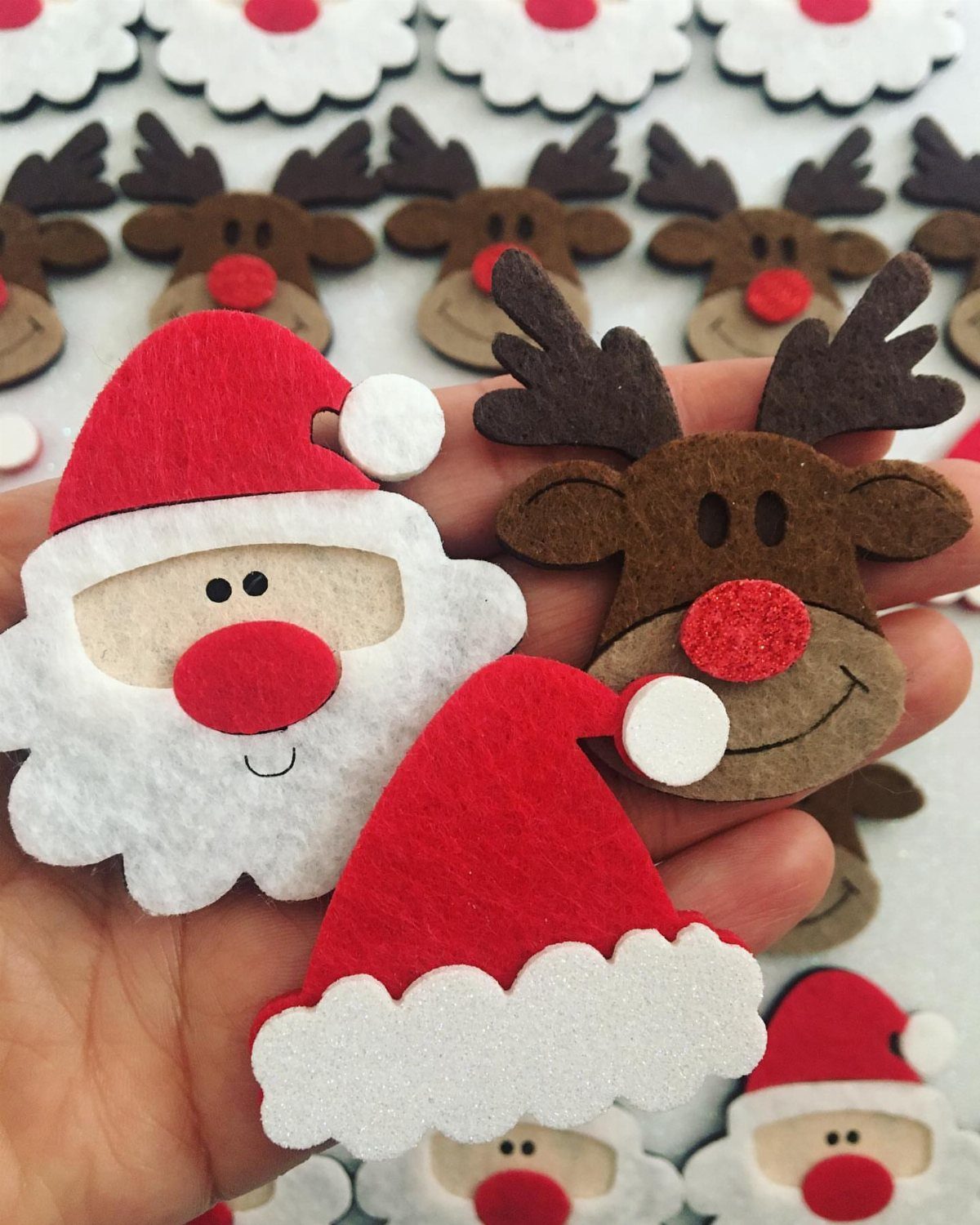 Santa and reindeer felt ornaments held in a hand with more in background