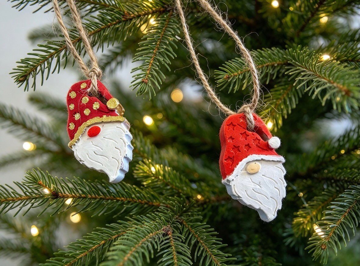 Two handmade gnome ornaments with red hats hanging on a lit Christmas tree.