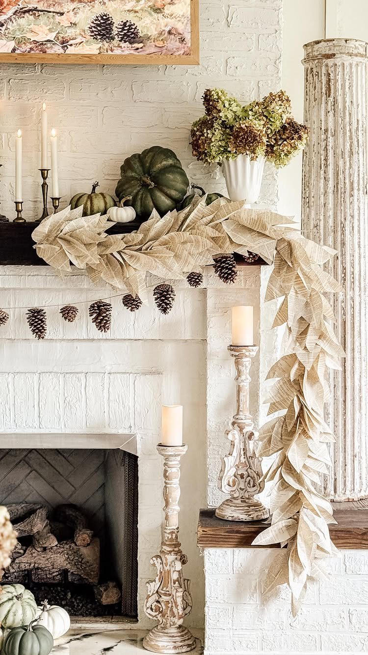 Beige leaf garland and pine cones draped over a white brick fireplace mantel