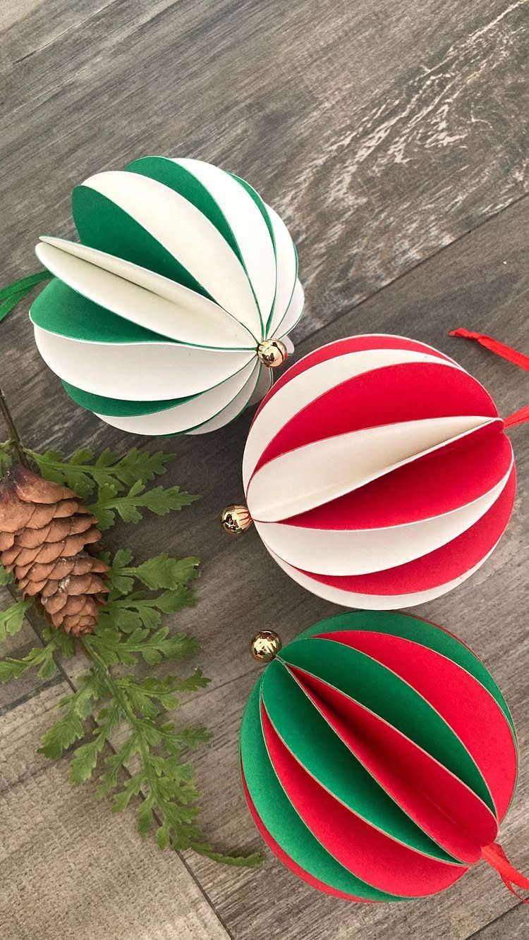 Three striped paper honeycomb ornaments in red, green, and white on wooden background.