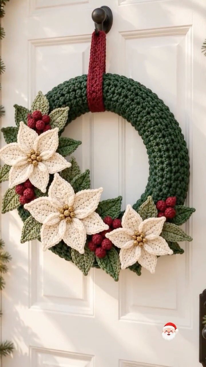 Crocheted green wreath with white poinsettia flowers and red berries on white door