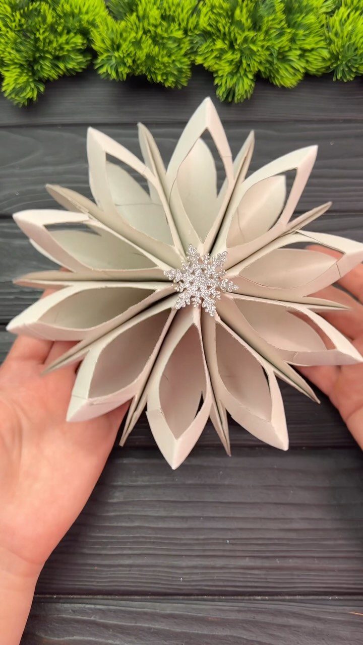 White star-shaped ornament made from cardboard tubes with a silver snowflake center.