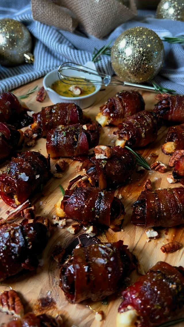 Bacon-wrapped water chestnuts on a wooden board with gold Christmas ornaments nearby.
