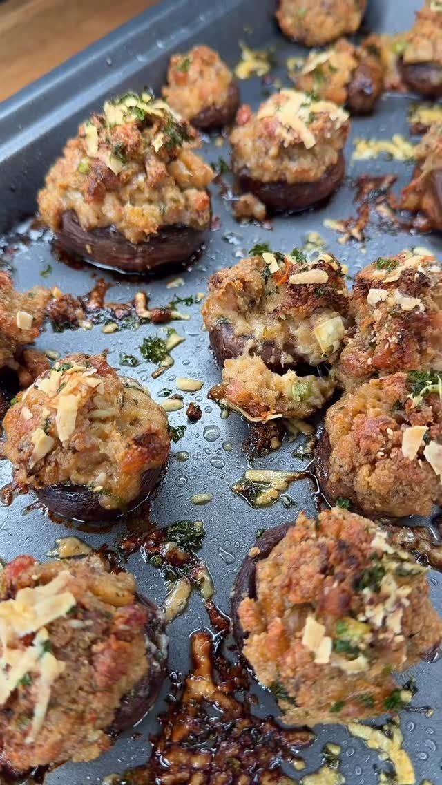 Stuffed mushroom caps with golden breadcrumbs and herbs on a baking sheet