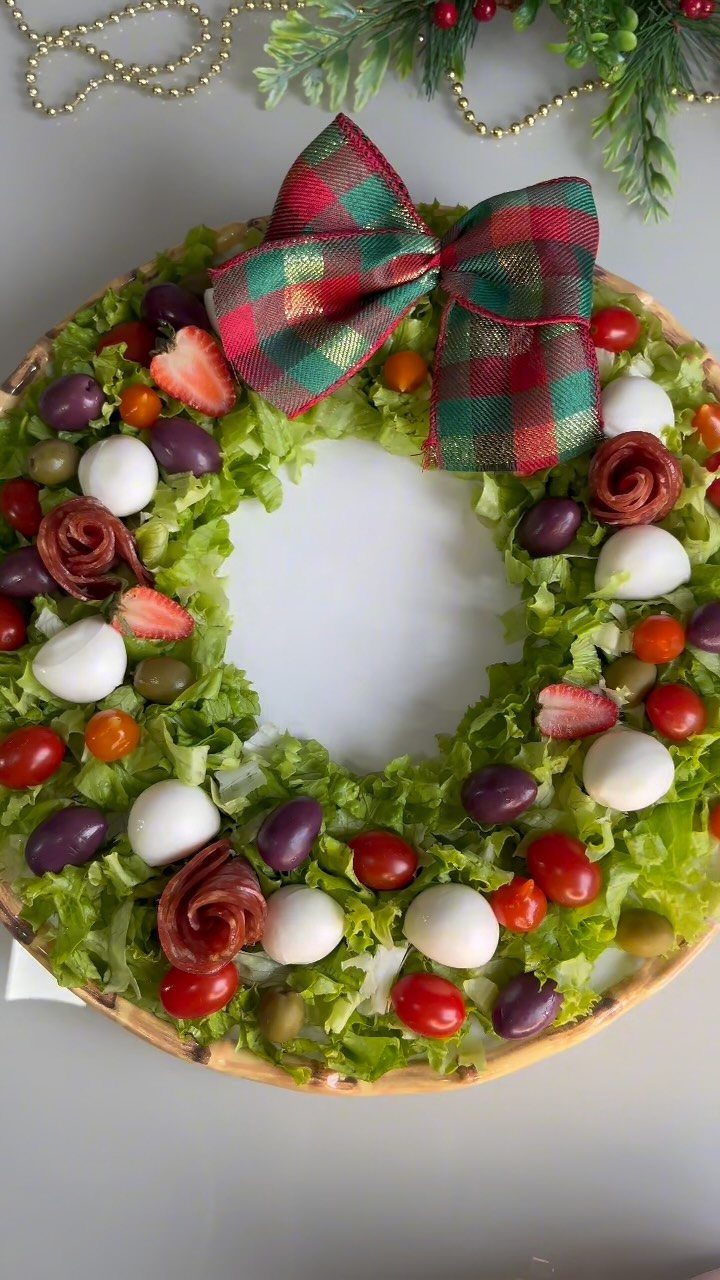 Wreath-shaped holiday salad with mozzarella, tomatoes, and olives topped with a plaid bow