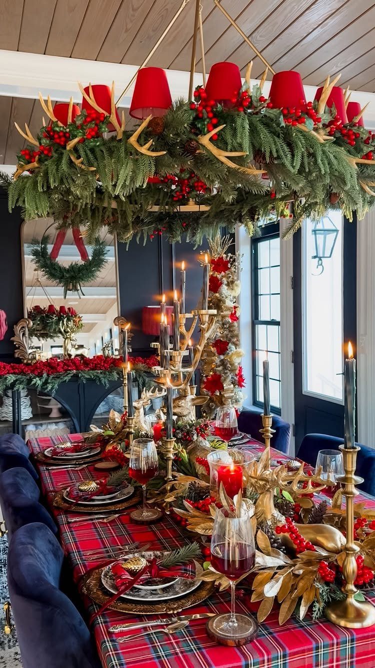 Evergreen garland with red berries draped over a chandelier above a festive tablescape