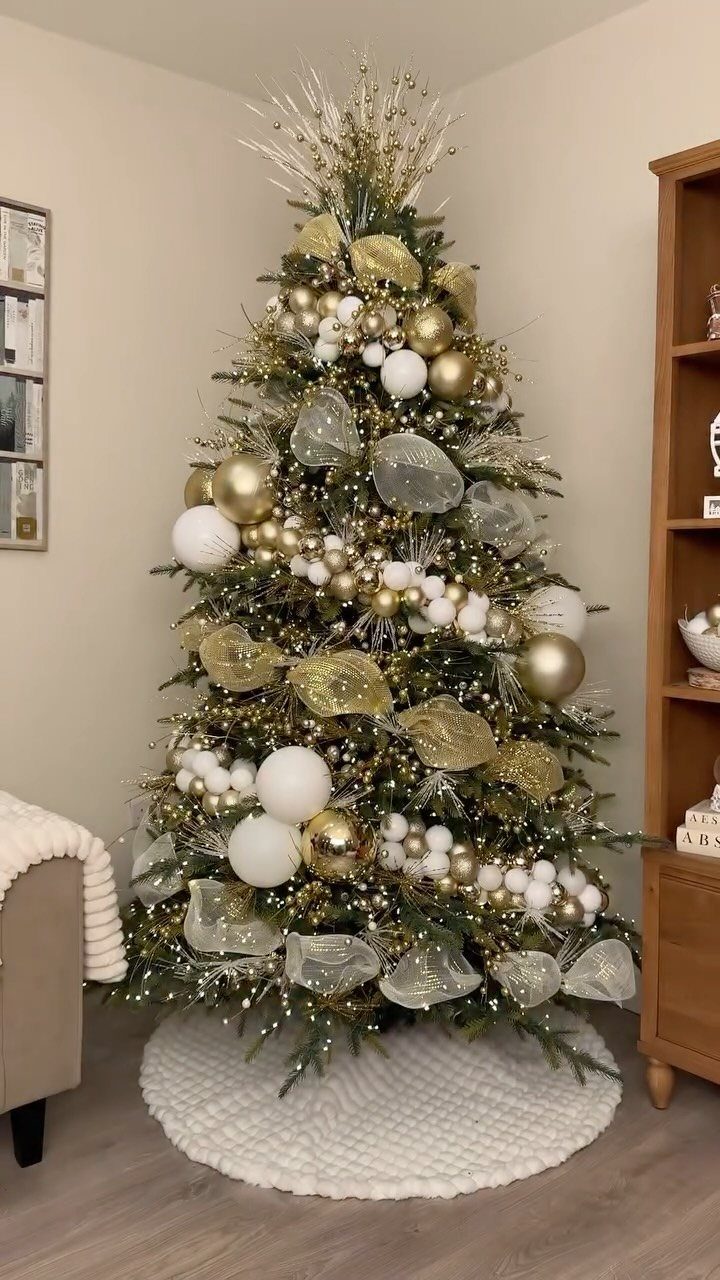 Decorated Christmas tree with gold and white ornaments and ribbons on white skirt