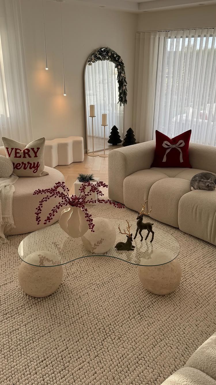 Cream living room with red Christmas pillows and berries on a glass table