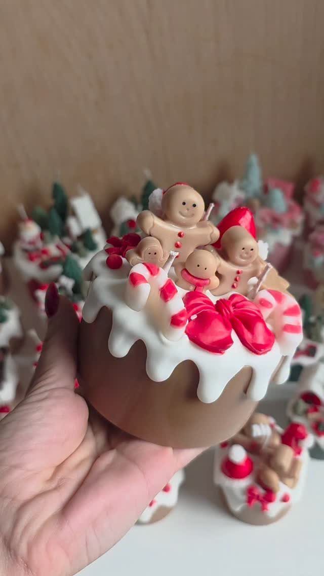 Cupcake-shaped Christmas candle with gingerbread men and candy canes held in a hand