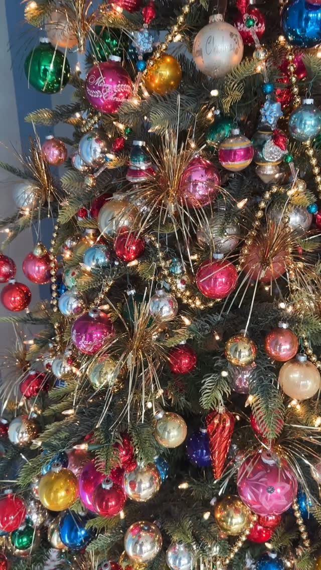 Colorful vintage glass ornaments and gold tinsel on a green Christmas tree