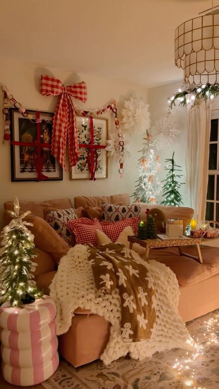 Cozy living room with string lights, small lit trees, and festive red decorations.