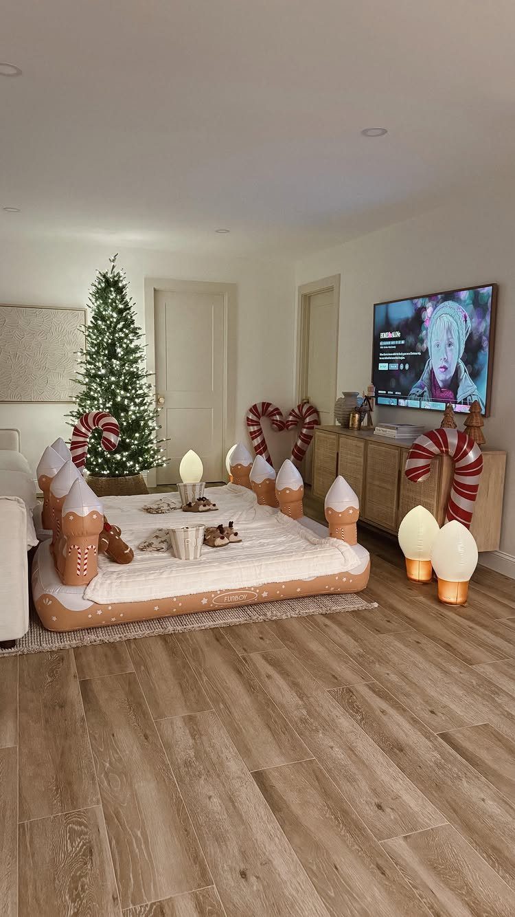 Inflatable gingerbread house bed in a living room with a Christmas tree and television.