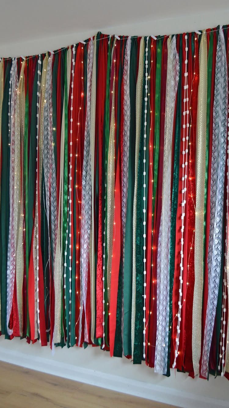 Festive backdrop of red, green, and gold fabric strips with twinkling fairy lights.