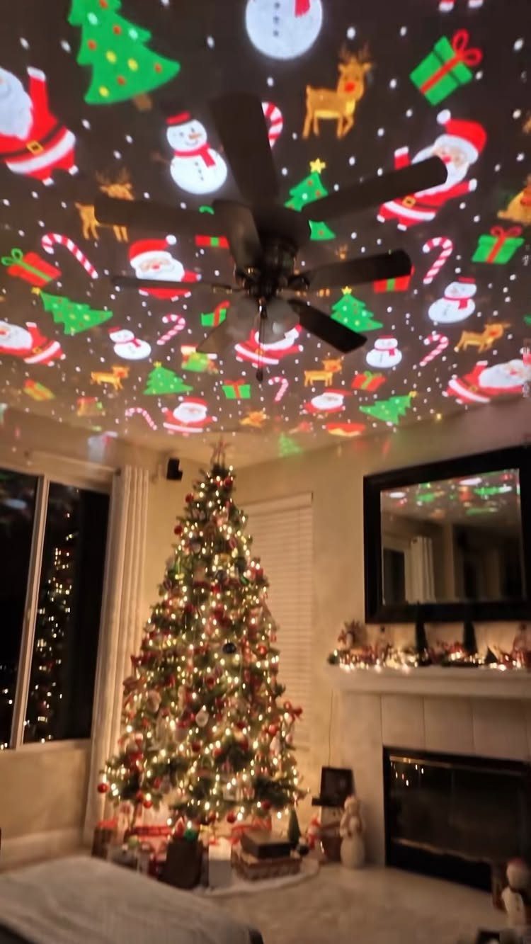 Christmas tree and fireplace with festive holiday light projections on the ceiling.