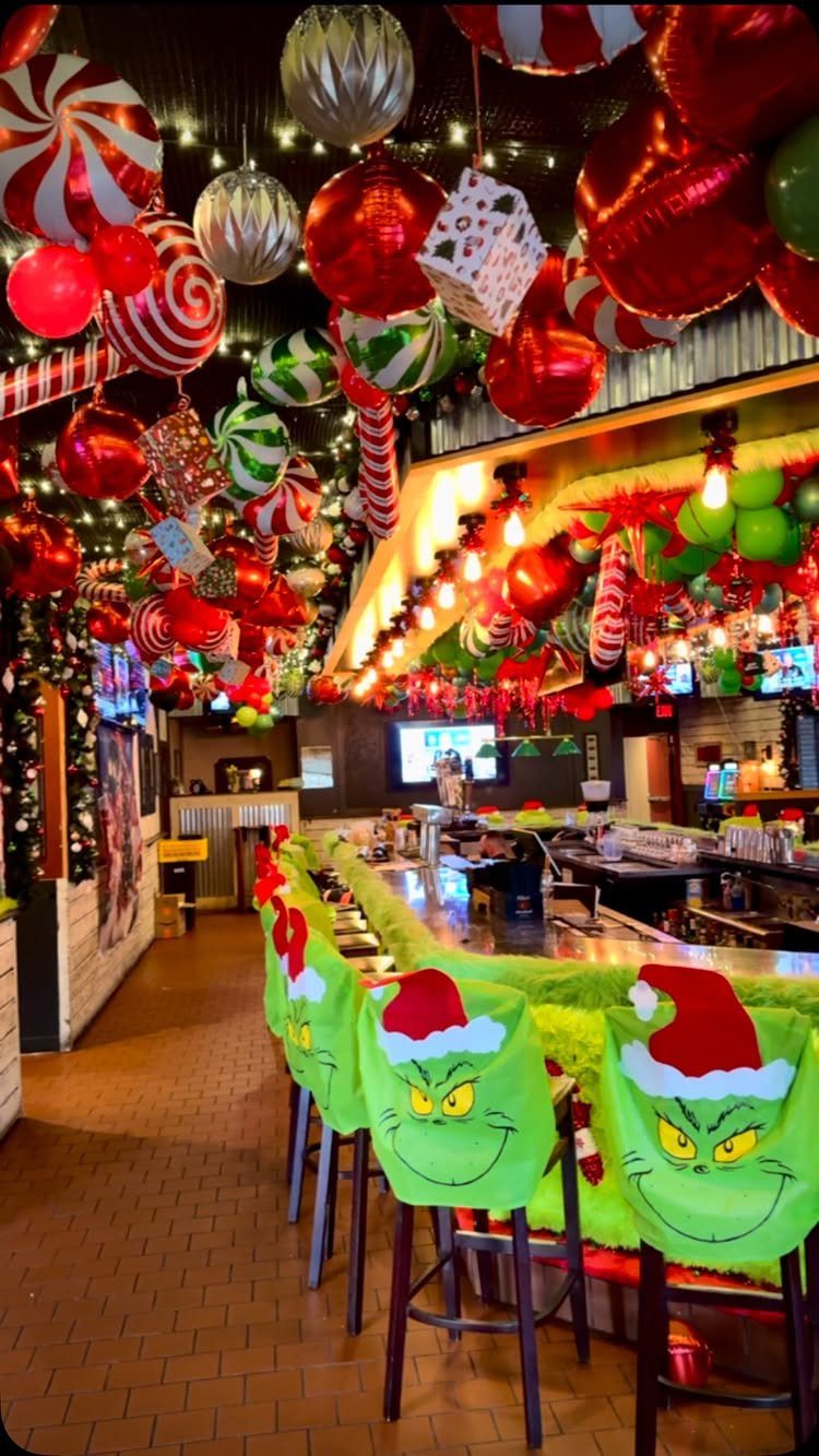 Festive bar interior with oversized Christmas ornaments and Grinch-themed bar stool covers.