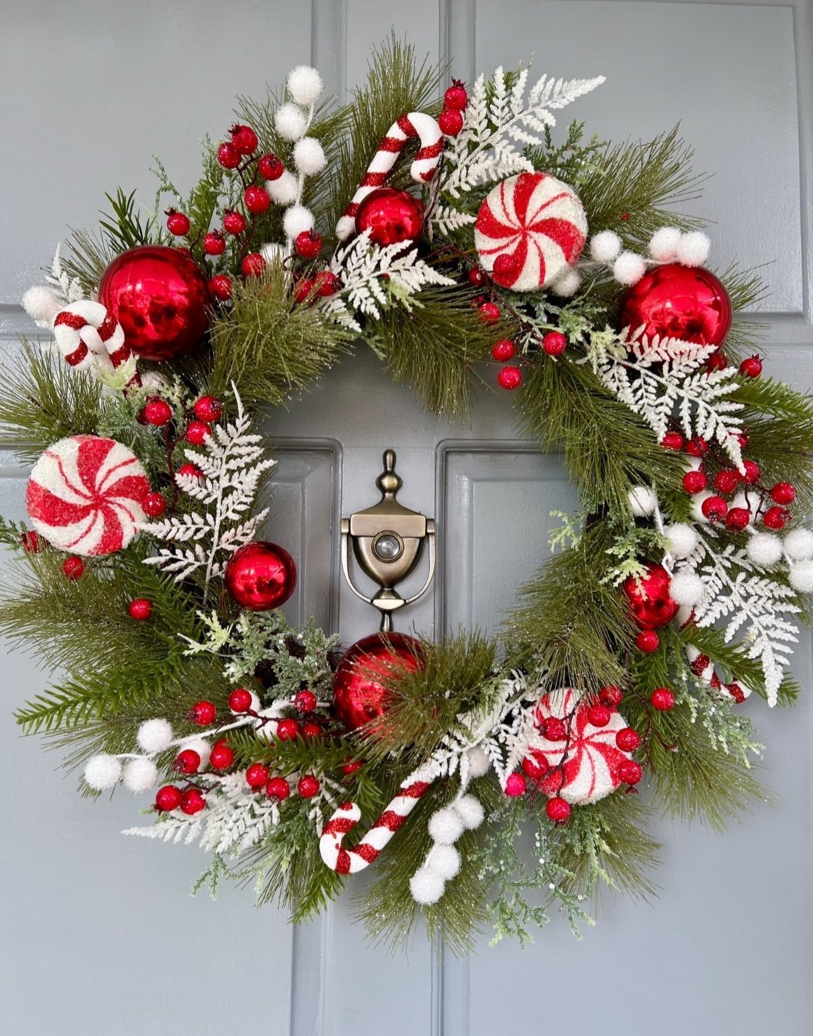 Festive Christmas wreath with candy canes and red ornaments on a grey door