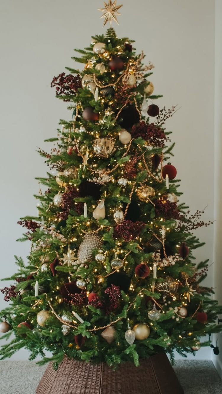 Decorated Christmas tree with red berry sprigs, gold ornaments, and warm white lights.