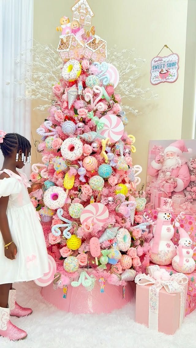 Pink Christmas tree decorated with giant candy ornaments and a girl in white.