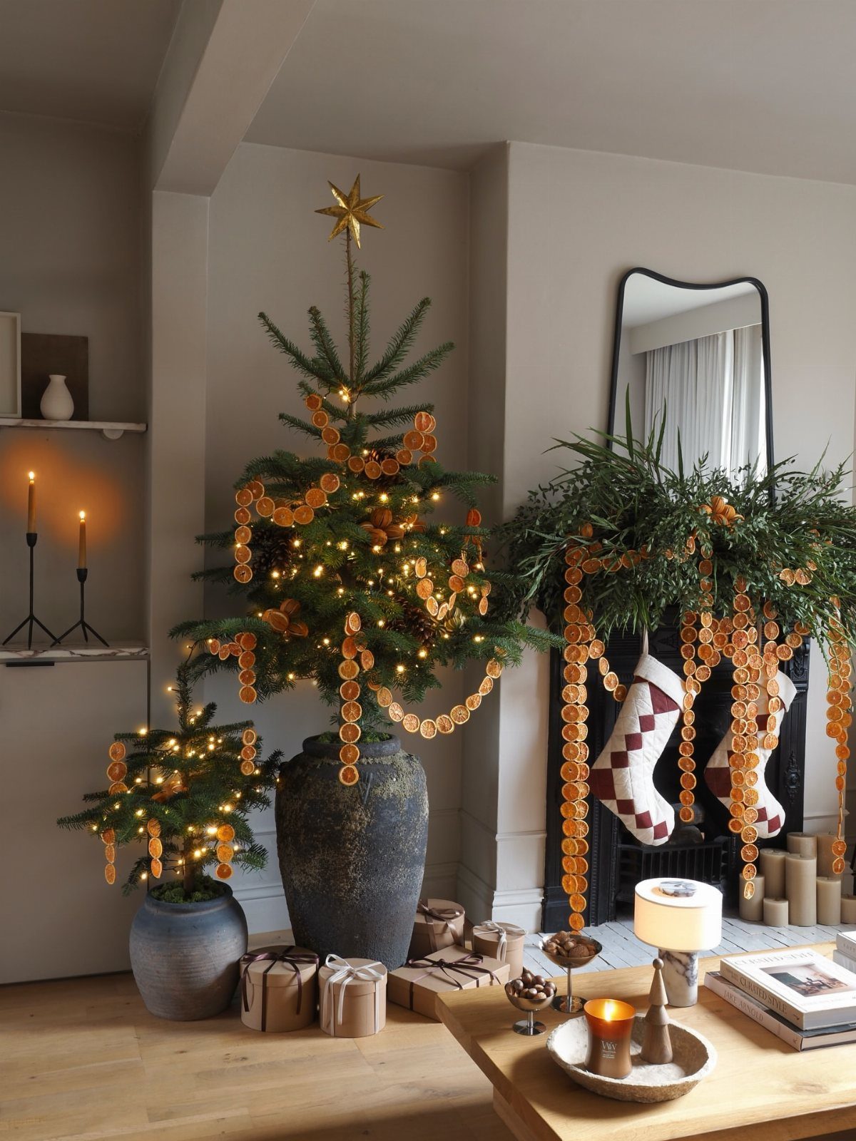 Christmas tree in a dark pot decorated with dried orange slice garlands and lights