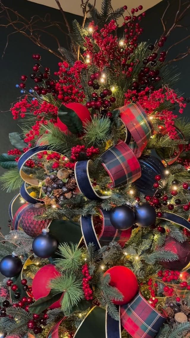 Decorated Christmas tree with red berries, blue ornaments, and plaid ribbons and lights.