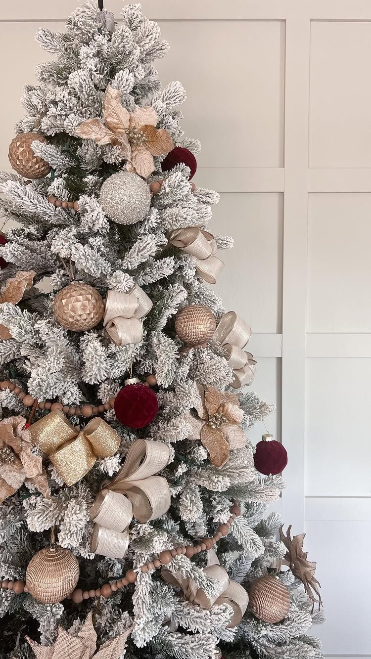 Flocked white Christmas tree with gold ribbons, red ornaments, and wooden bead garlands.