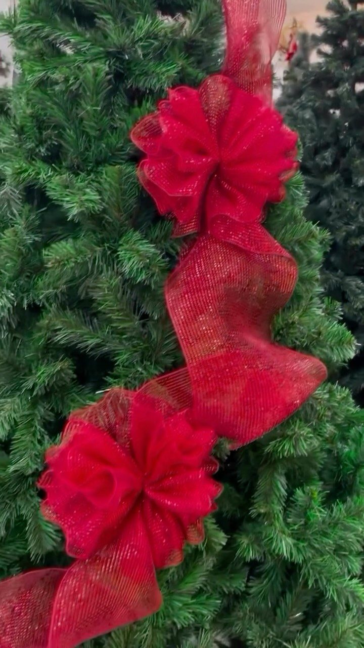 Red shimmering wired ribbon with bows draped on a green Christmas tree