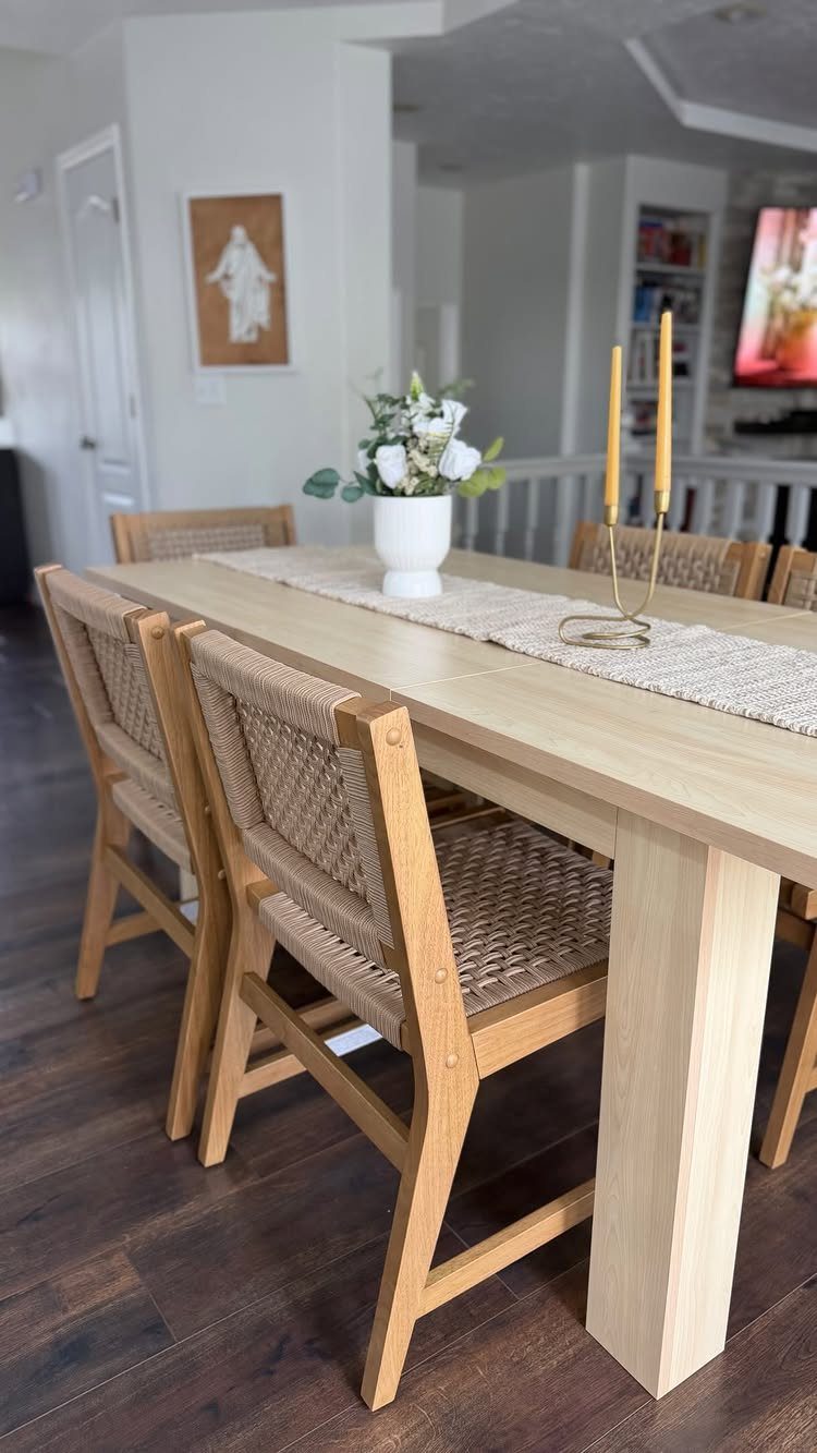 Light wood dining table and woven chairs in a bright contemporary farmhouse room.