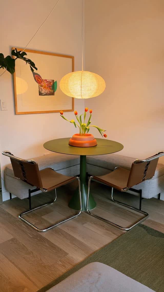 L-shaped grey corner banquette with a round green table and leather chairs.