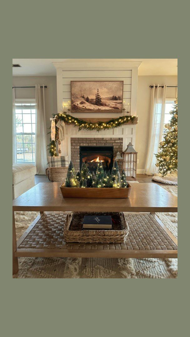 Wooden coffee table with a tray of mini lit Christmas trees in a cozy room.